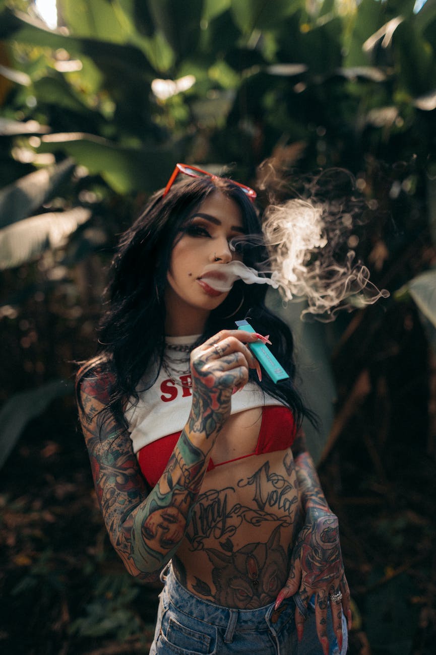 woman in black and red floral long sleeve shirt smoking | E-Cigarette advertising and using is danger and cause cancer | India Banned E-Cigarette